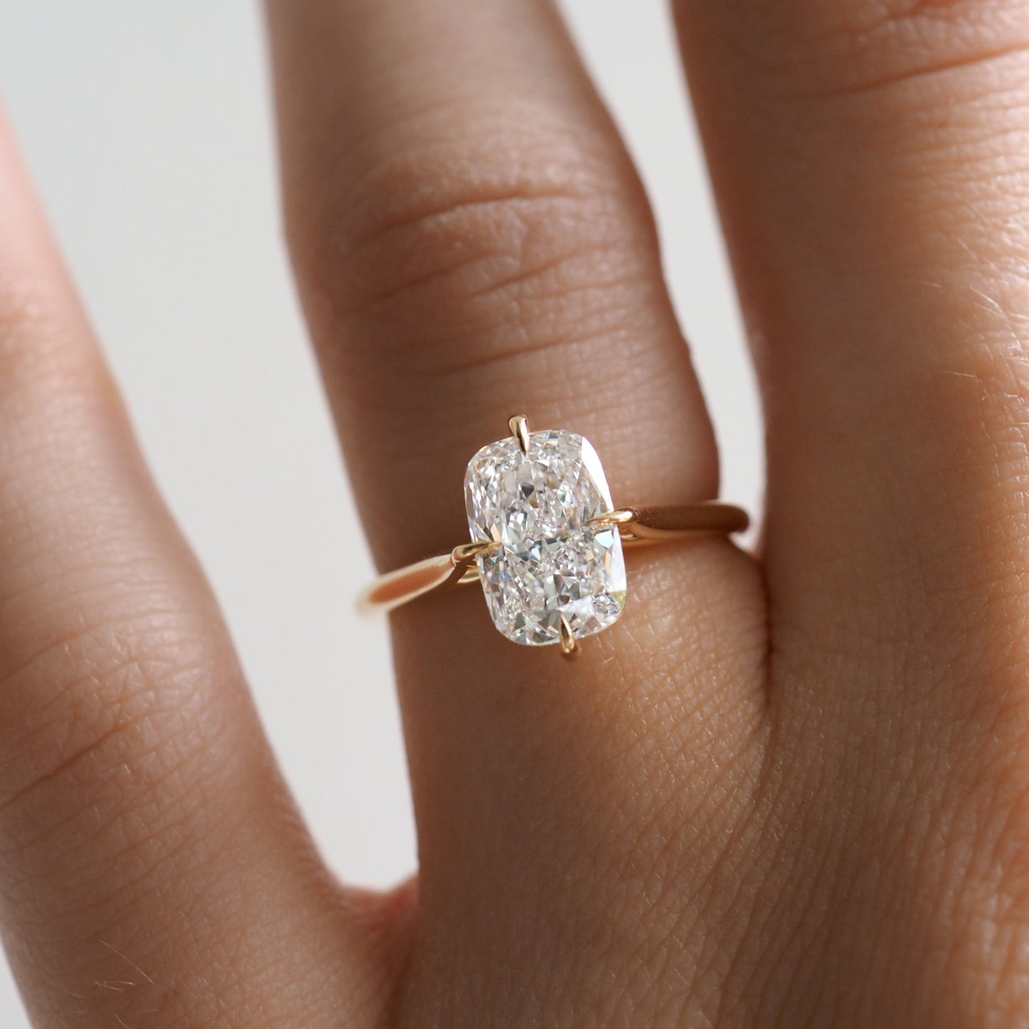 Close-up of a hand wearing a gold ring with a large cushion-cut diamond, symbolising luxury jewellery.
