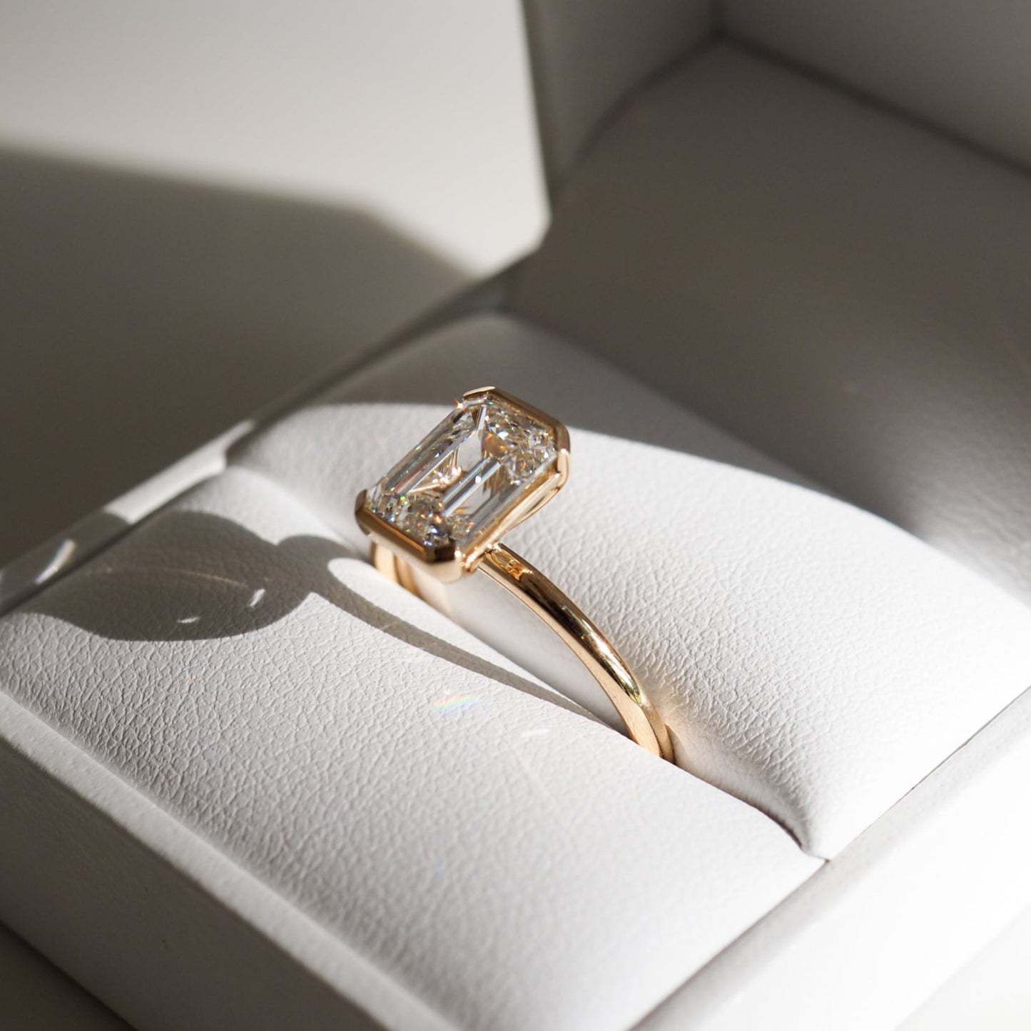 Emerald-cut diamond ring with gold band in an open white jewellery box, showcasing luxury and elegance in fine Australian jewellery.