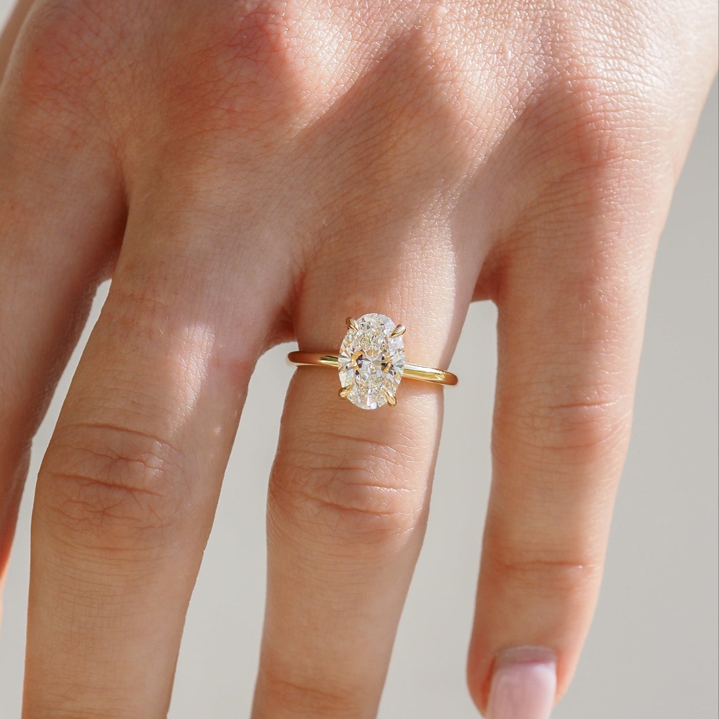 A hand displaying an oval diamond ring with a gold band, capturing a sense of luxury and elegance.