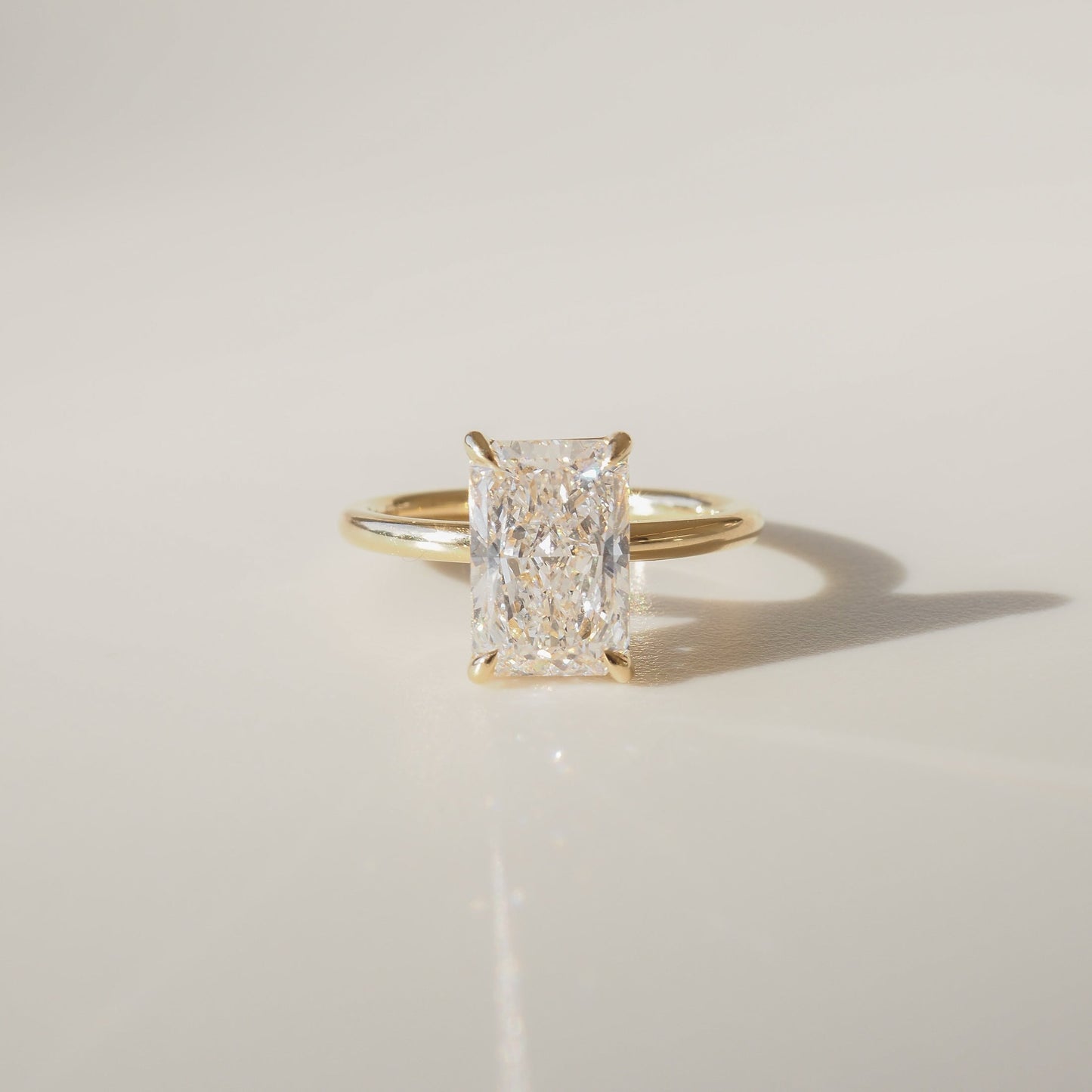 Gold ring with a radiant-cut diamond, elegantly displayed against a neutral background. Perfect for luxury jewellery lovers.